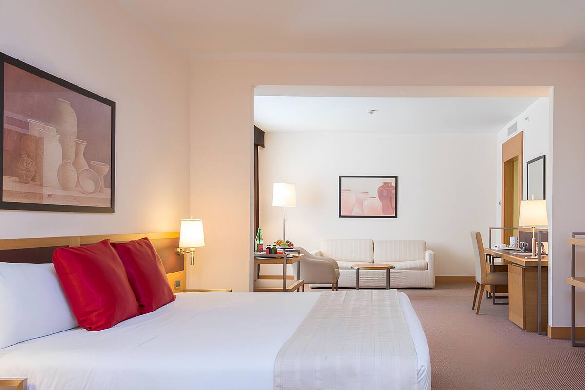 Habitación de hotel con una cama grande, un escritorio, una silla, un sofá y dos lámparas.