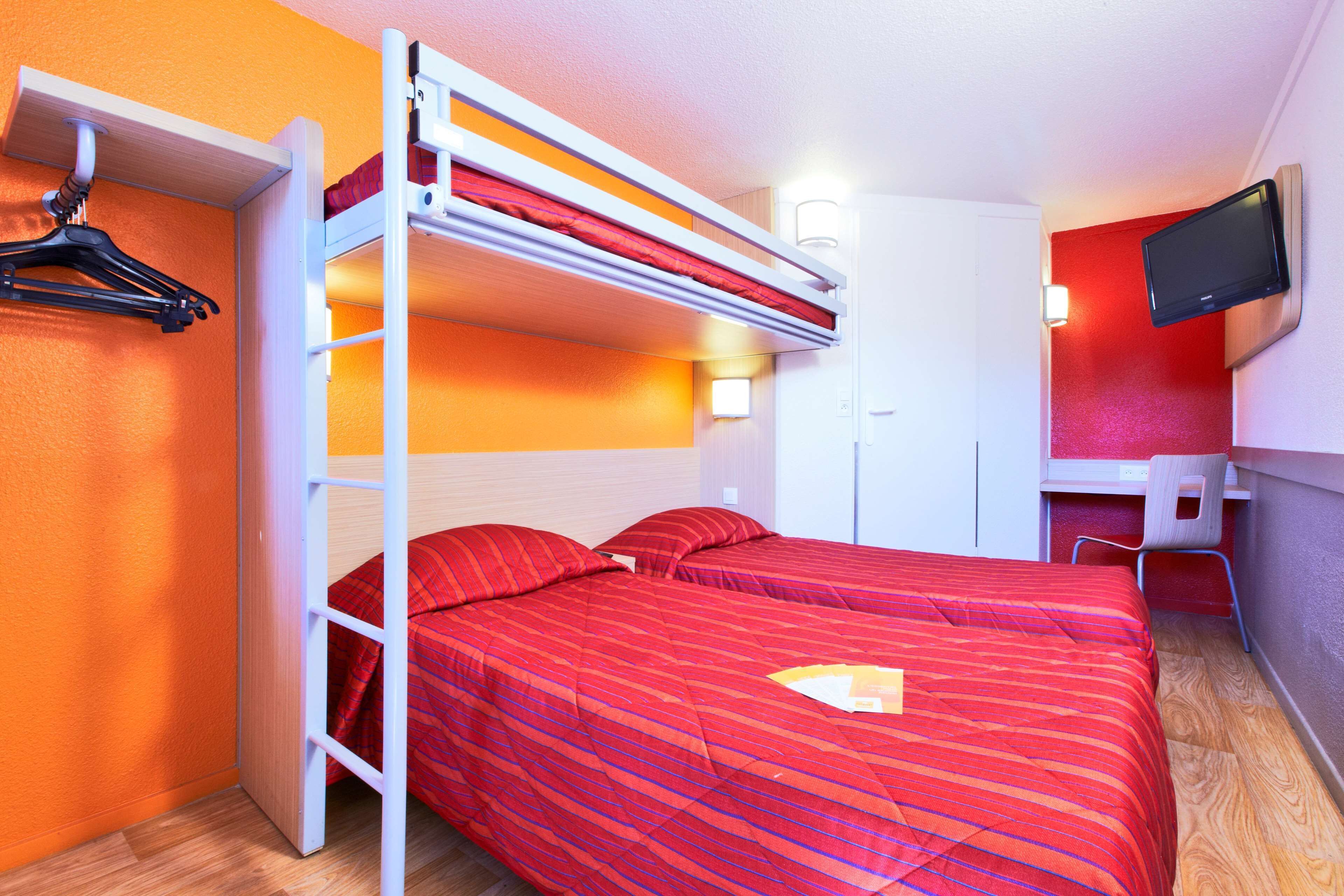 A bunk bed room with a desk and a TV.