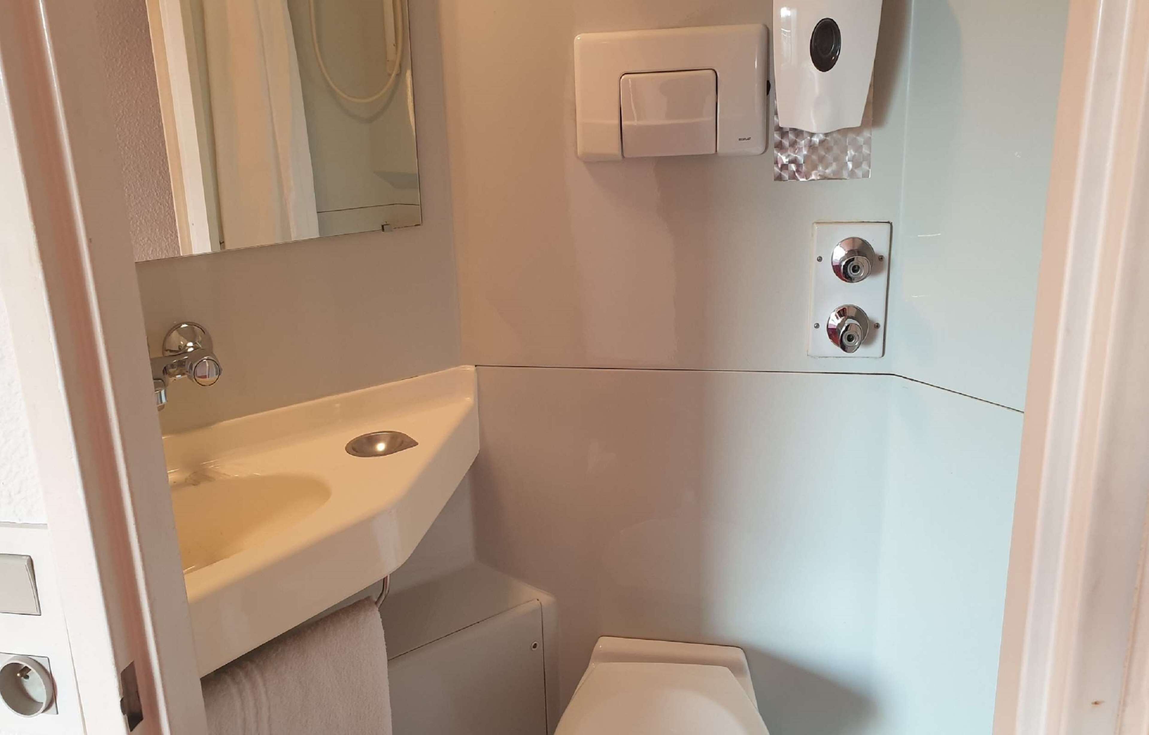 A bathroom with a sink, toilet, and a mirror.