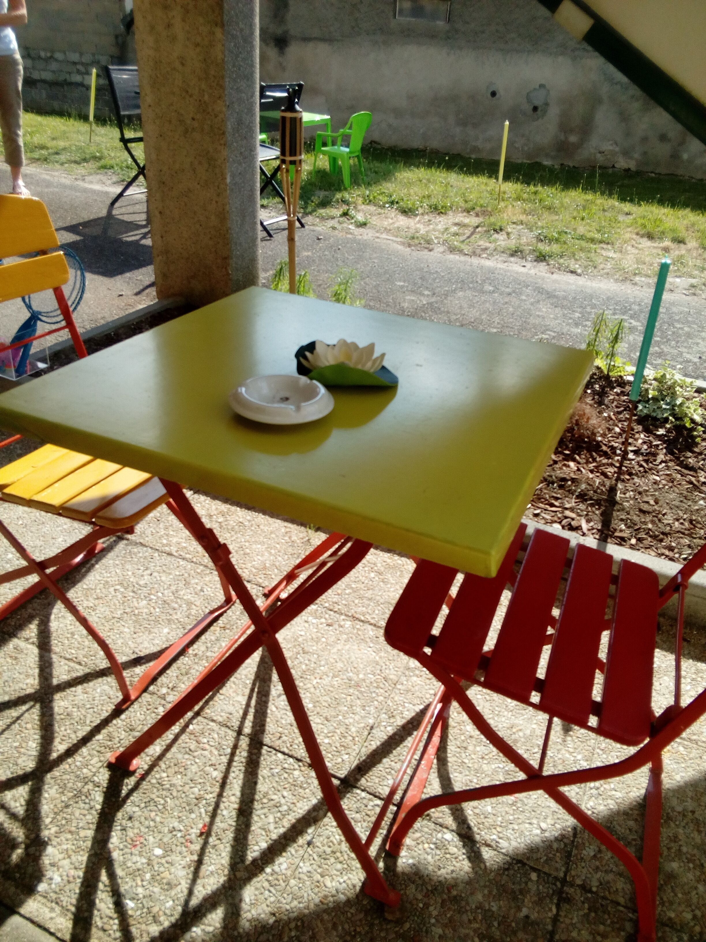 A yellow table with a white ashtray and a green leaf-shaped object on it.