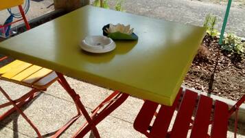 A yellow table with a white ashtray and a green leaf-shaped object on it.