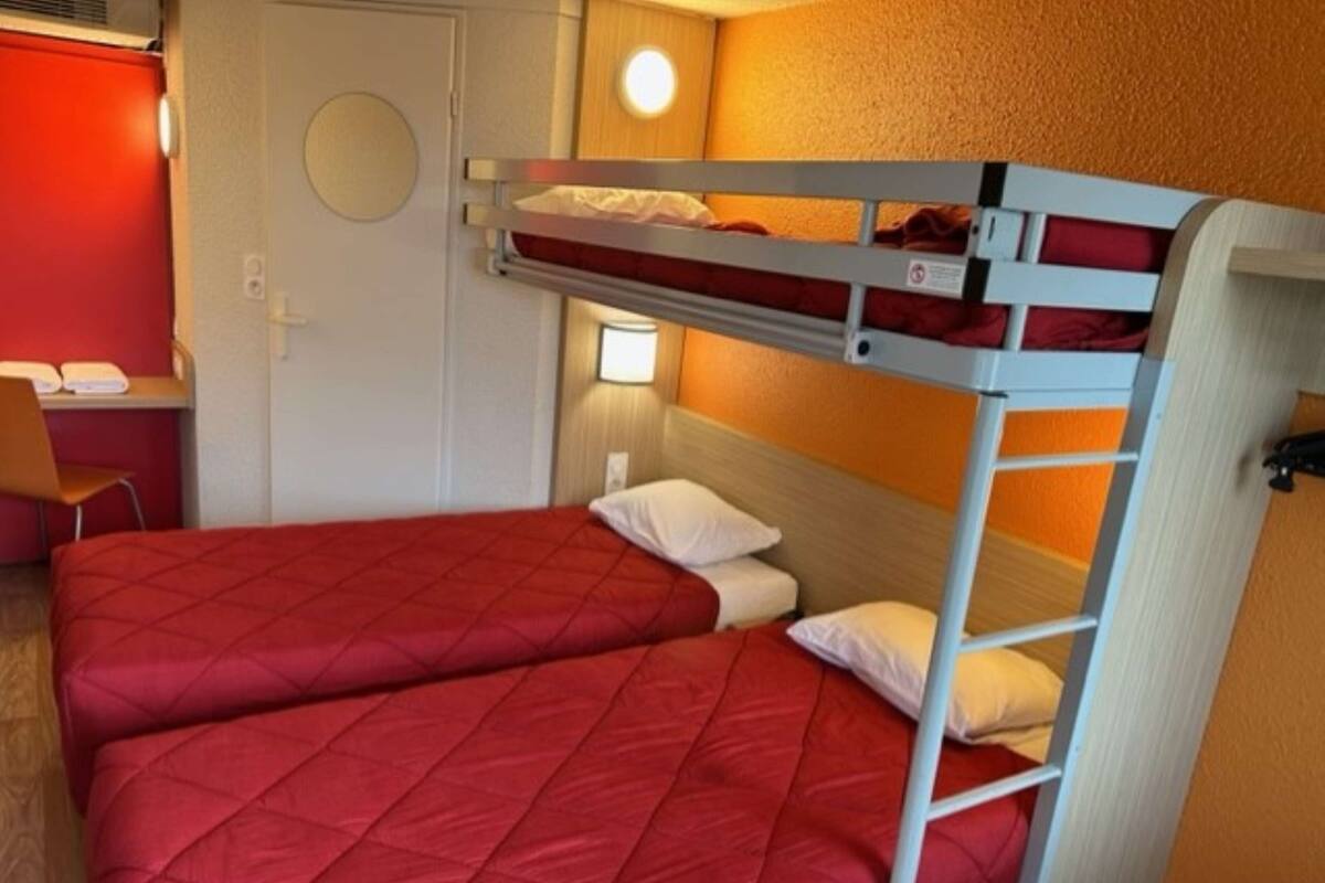 A bunk bed room with two beds, a desk, and a chair.