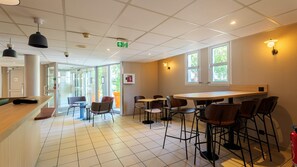 L’intérieur d’un café moderne, avec un bar, des tables et de grandes fenêtres.