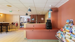 Een restaurant met een toonbank, stoelen, een brandblusser, een koffieapparaat en een boekenpresentatie.
