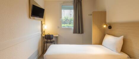 A hotel room with two beds, a desk, a chair, a TV, and a window with curtains.