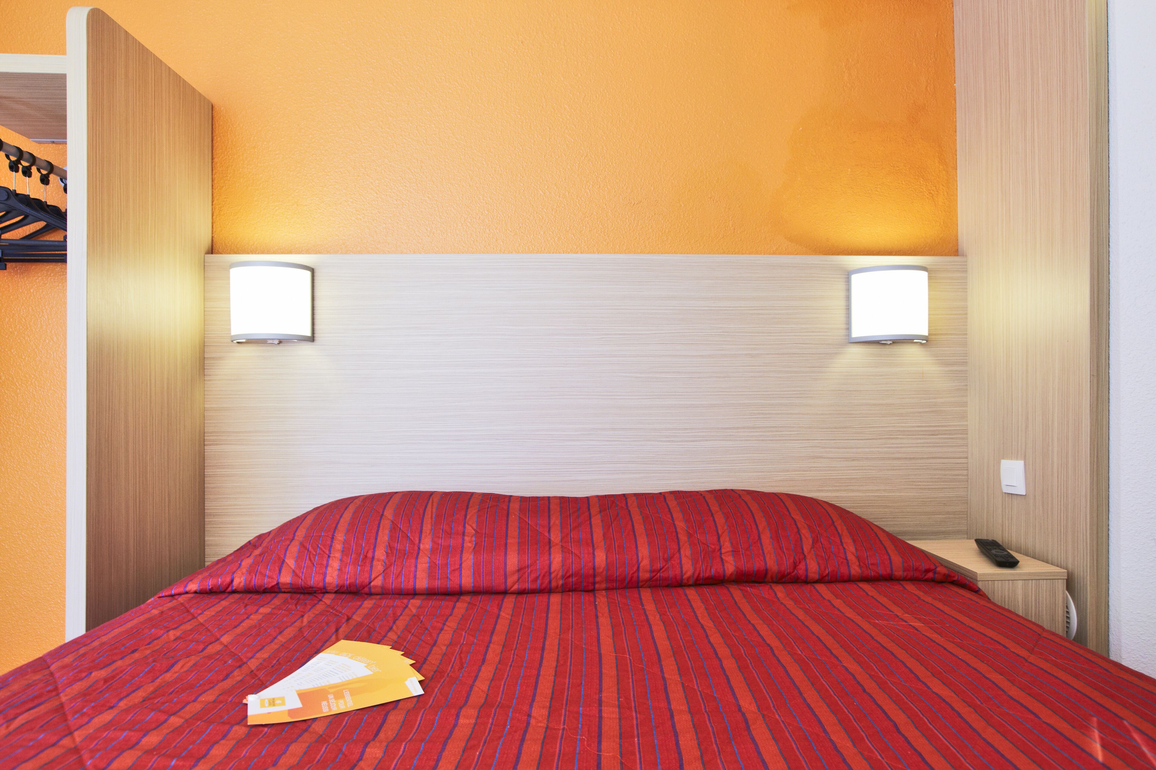 A hotel room with a bed, two bedside lamps, and a nightstand with a phone.