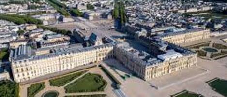 Vista aérea de un extenso complejo de edificios históricos con jardines simétricos y un patio central.
