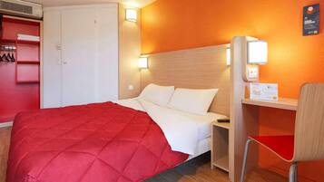 Une chambre d’hôtel avec un lit, un bureau, une chaise et une armoire.