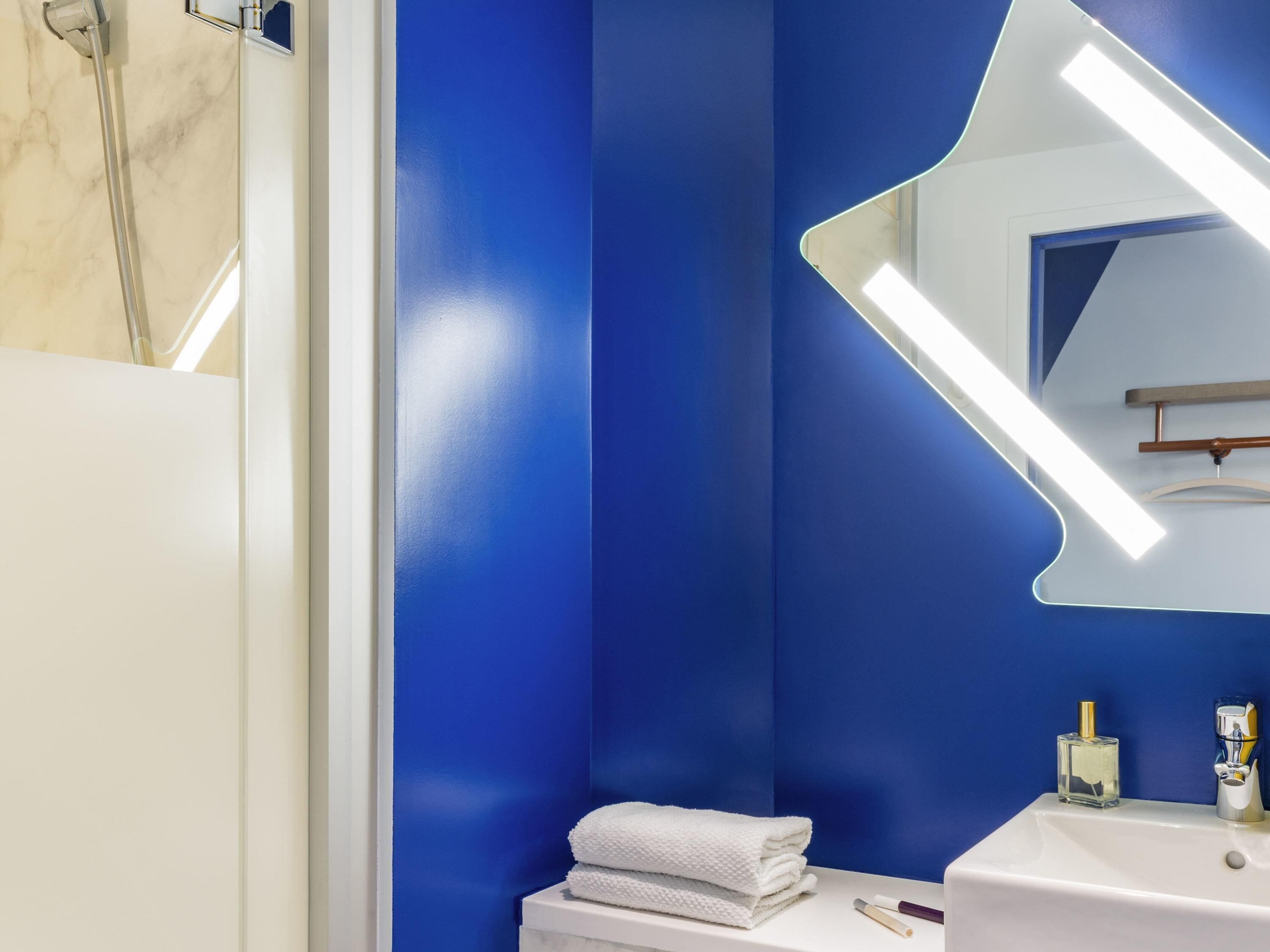 A bathroom with a blue wall, a white sink, a mirror, and a towel.
