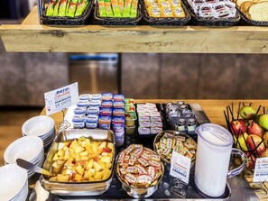 A buffet with various food items, including fruits, pastries, and dairy products. - ibis Budget Marne-la-Vallée Noisy-le-Grand (Noisy-le-Grand)