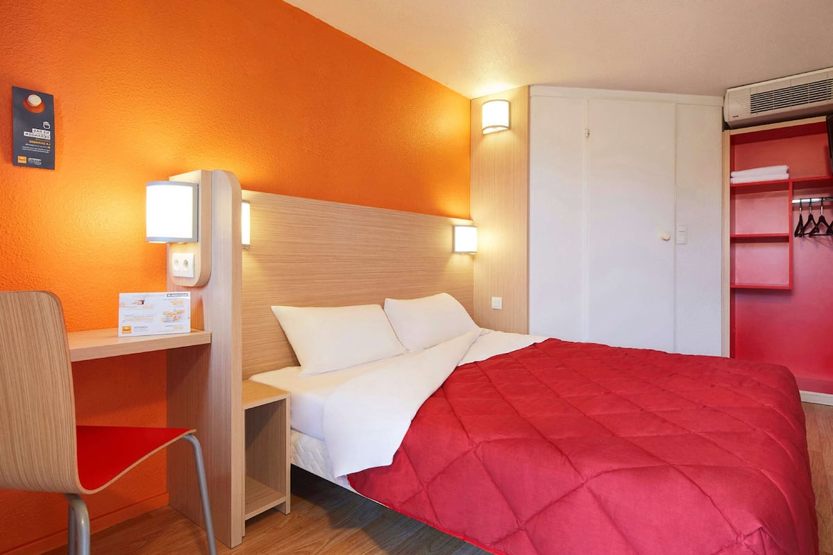 A hotel room with a bed, a desk, and a wardrobe.