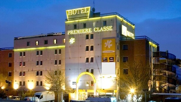 Un hotel con un llamativo letrero que dice "HOTEL PREMIERE CLASSE", varios pisos y un diseño arquitectónico moderno.