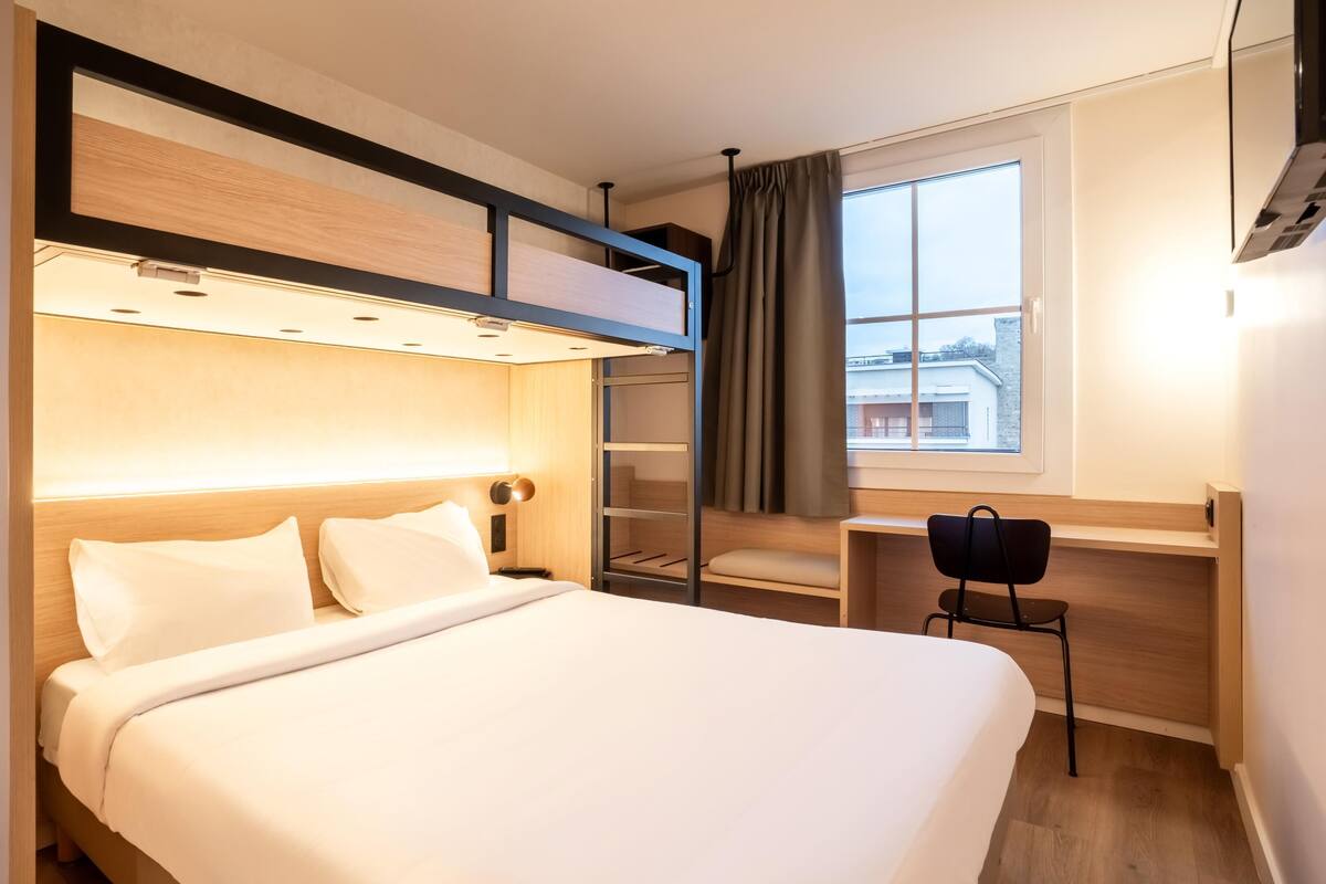Una habitación de hotel moderna con una cama, una mesita de noche y un escritorio con silla.