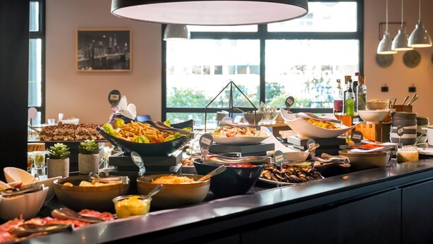 Un bufé con diferentes opciones de comida y un ventanal grande al fondo.