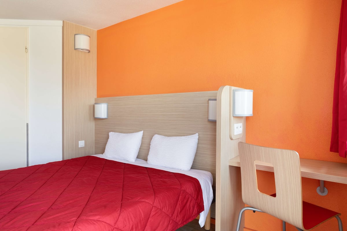 A hotel room with a bed, a desk, and a chair.
