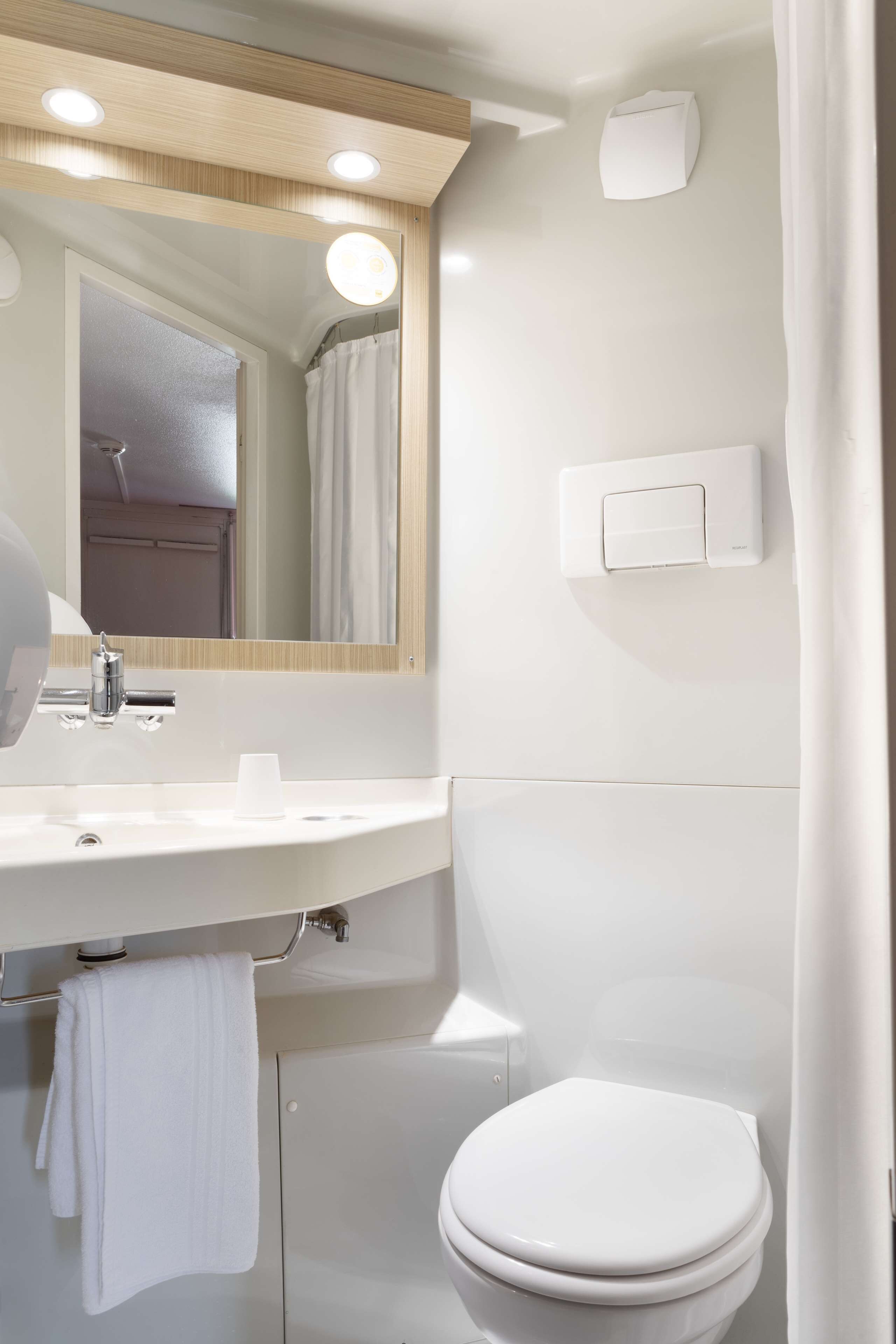 Un baño moderno con lavamanos, espejo y retrete blancos.