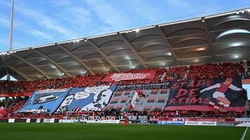 A stadium with a large crowd, banners, and advertisements.