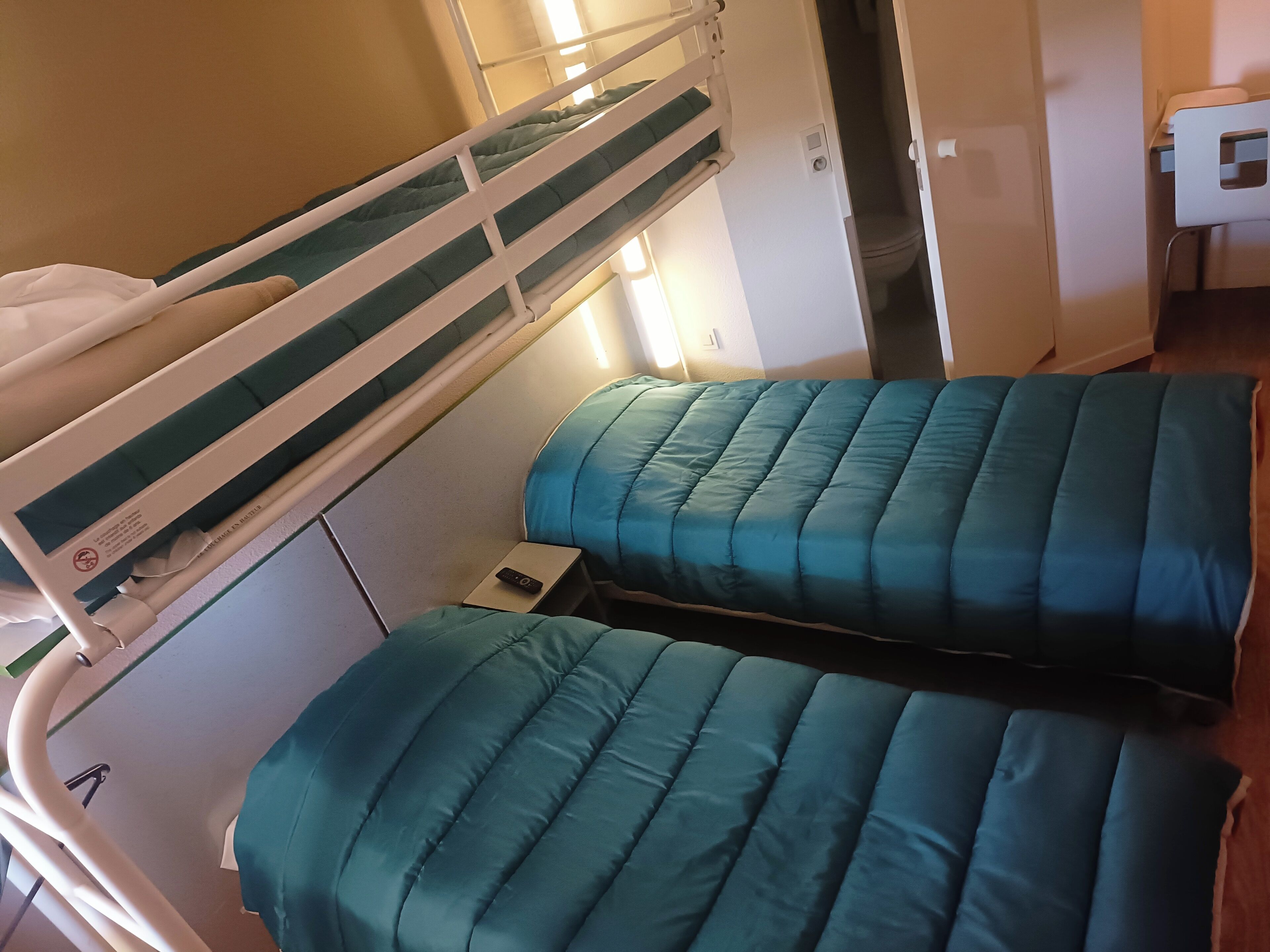 A bunk bed with a control panel and a small bedside table.