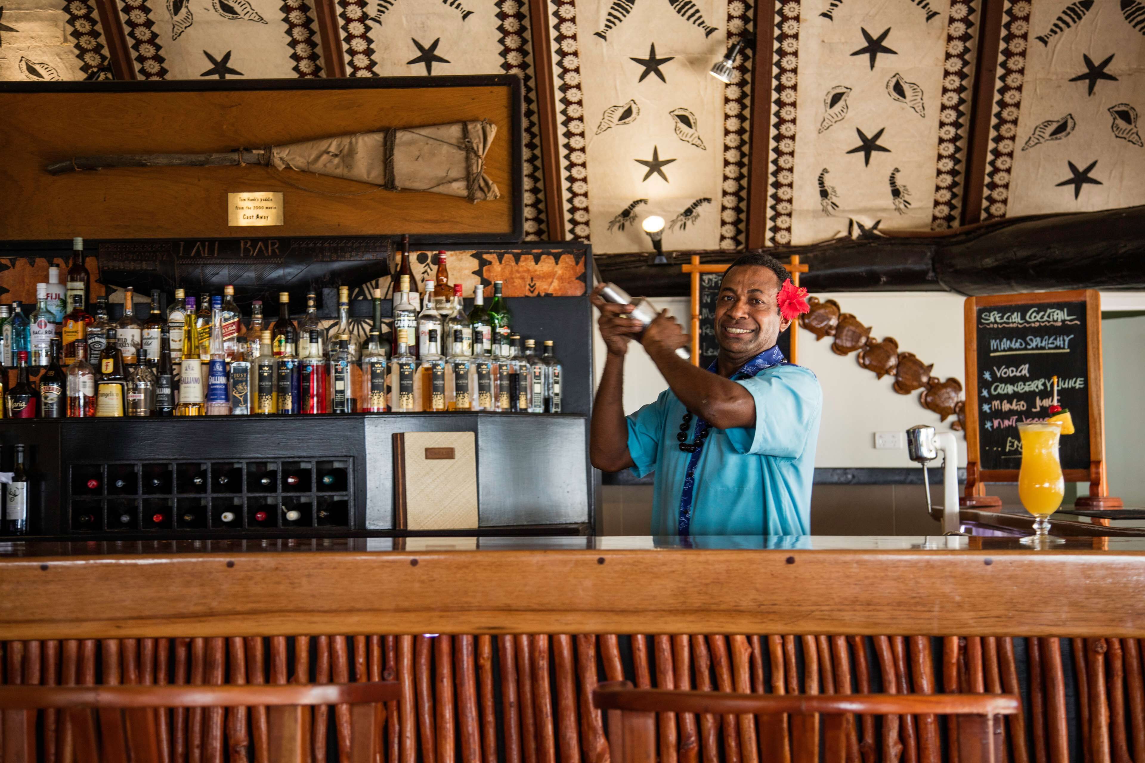 A bar with a variety of liquor bottles, a chalkboard menu, and a wooden ceiling with star patterns.