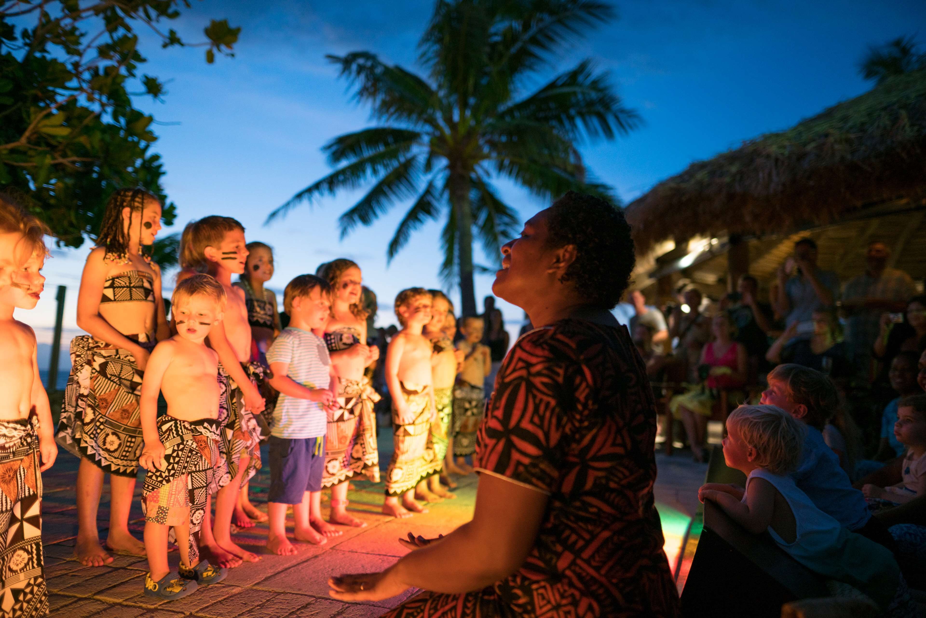 A group of people standing on a tiled floor with palm trees in the background.