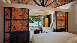A hotel room with a bed, a small table, and a view of the beach. - Castaway Island, Fiji (Castaway Island)