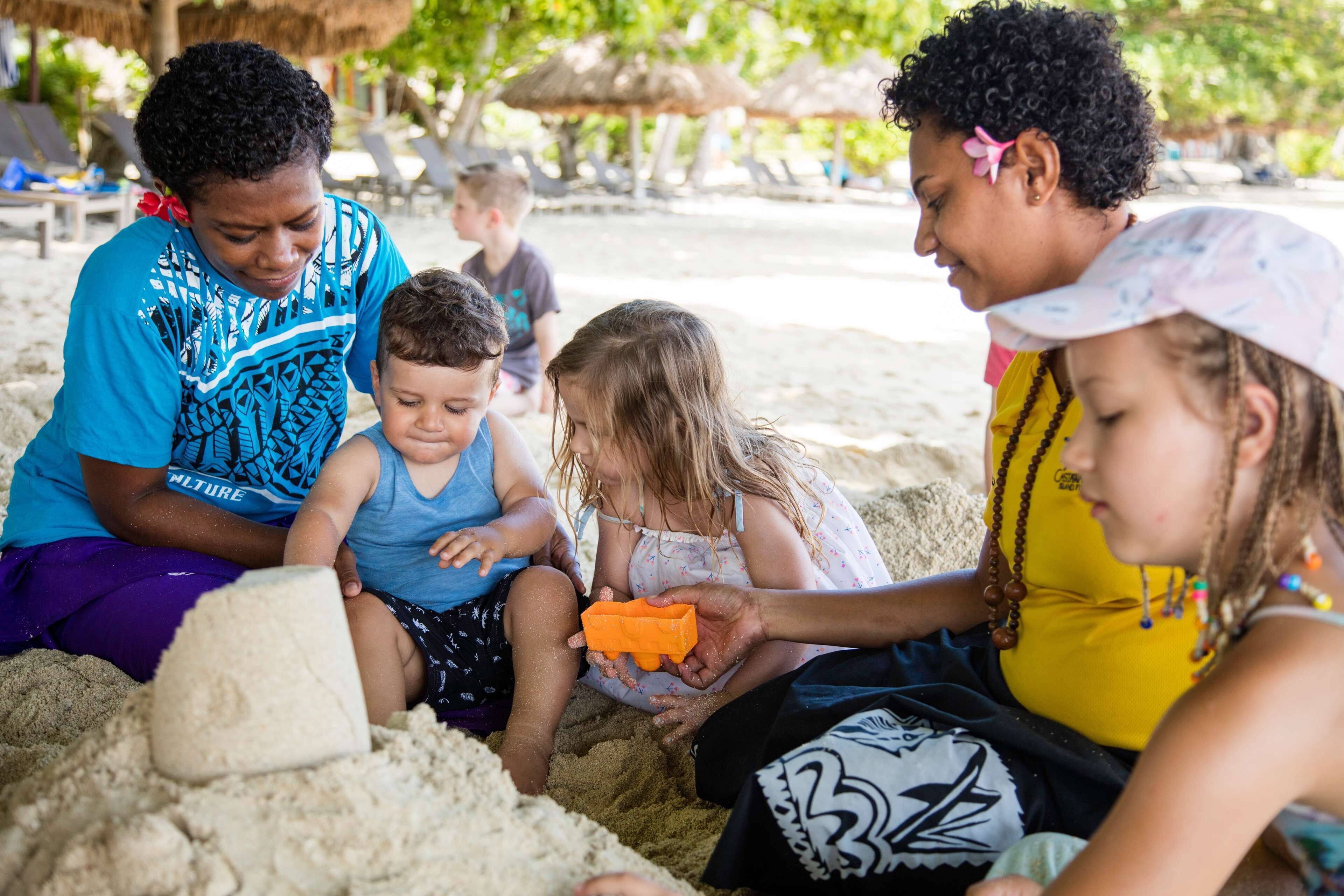 A group of people sitting on the sand, engaged in an activity.