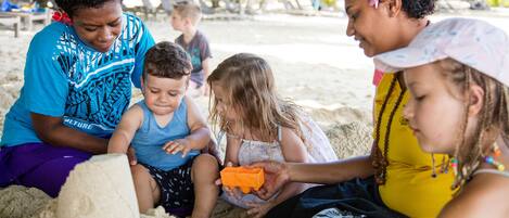 A group of people sitting on the sand, engaged in an activity.