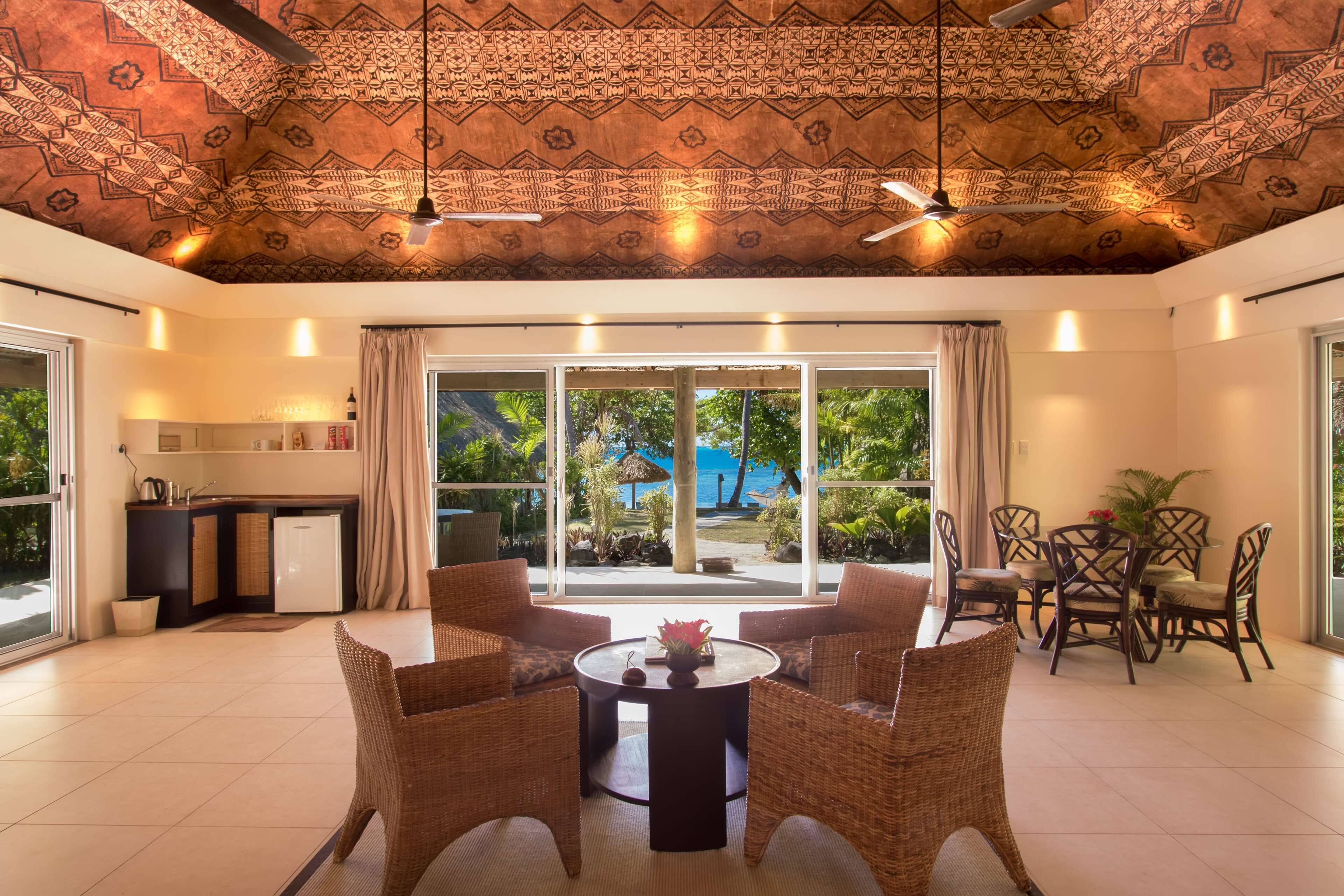 A spacious room with a dining area, a kitchen, and a large sliding glass door leading to a garden.