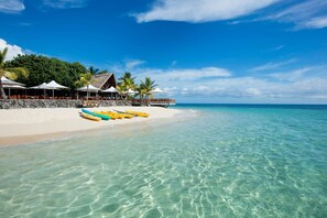 Privat strand, hvit sand, solsenger og parasoller