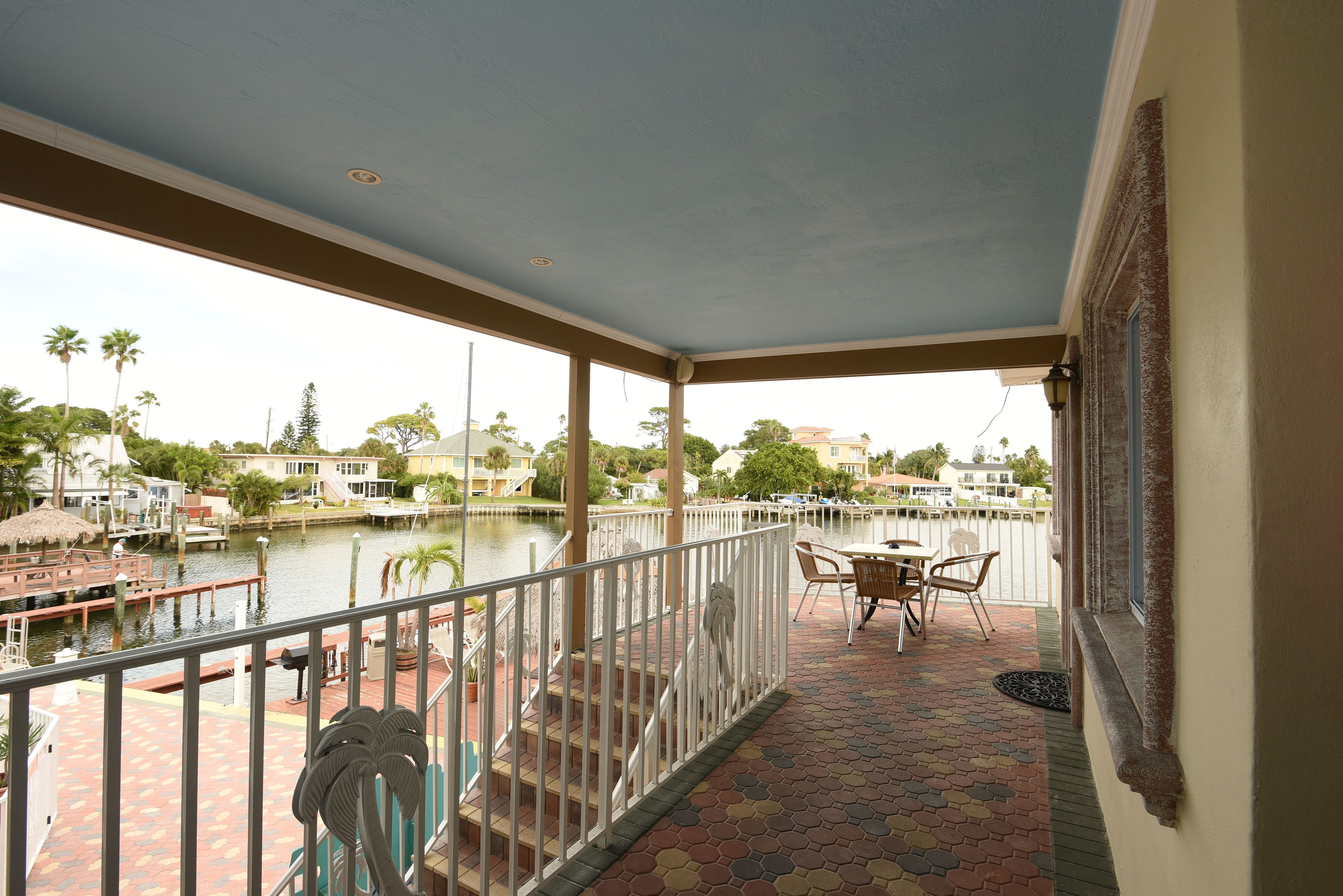 Ein überdachter Balkon mit Blick auf eine Marina, Sitzgelegenheiten im Freien und einem Geländer.