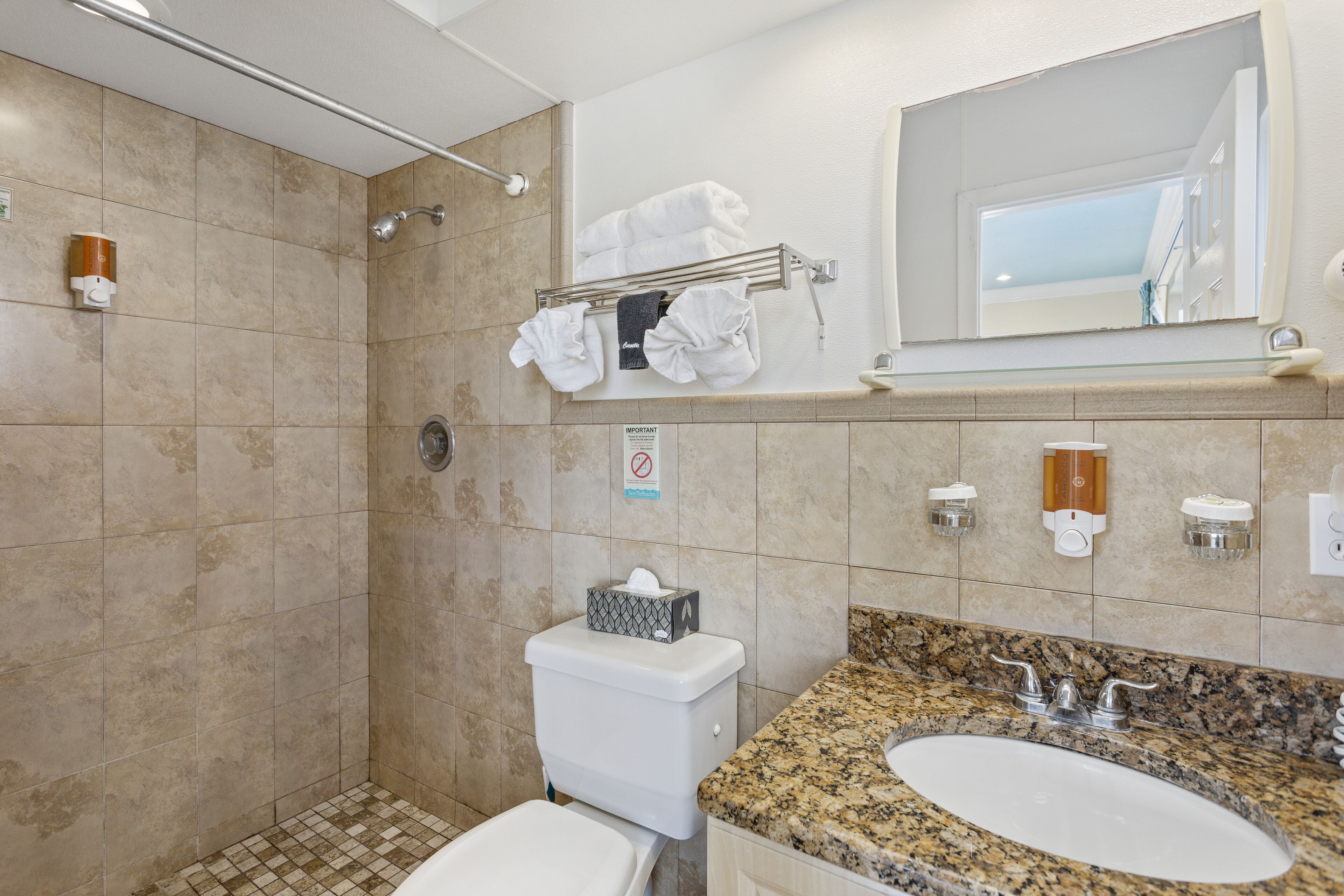 Un baño con ducha, inodoro, lavabo y toallero.