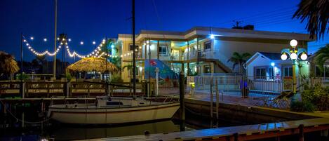 A waterfront property with a dock, a boat, and a house with multiple levels and balconies.
