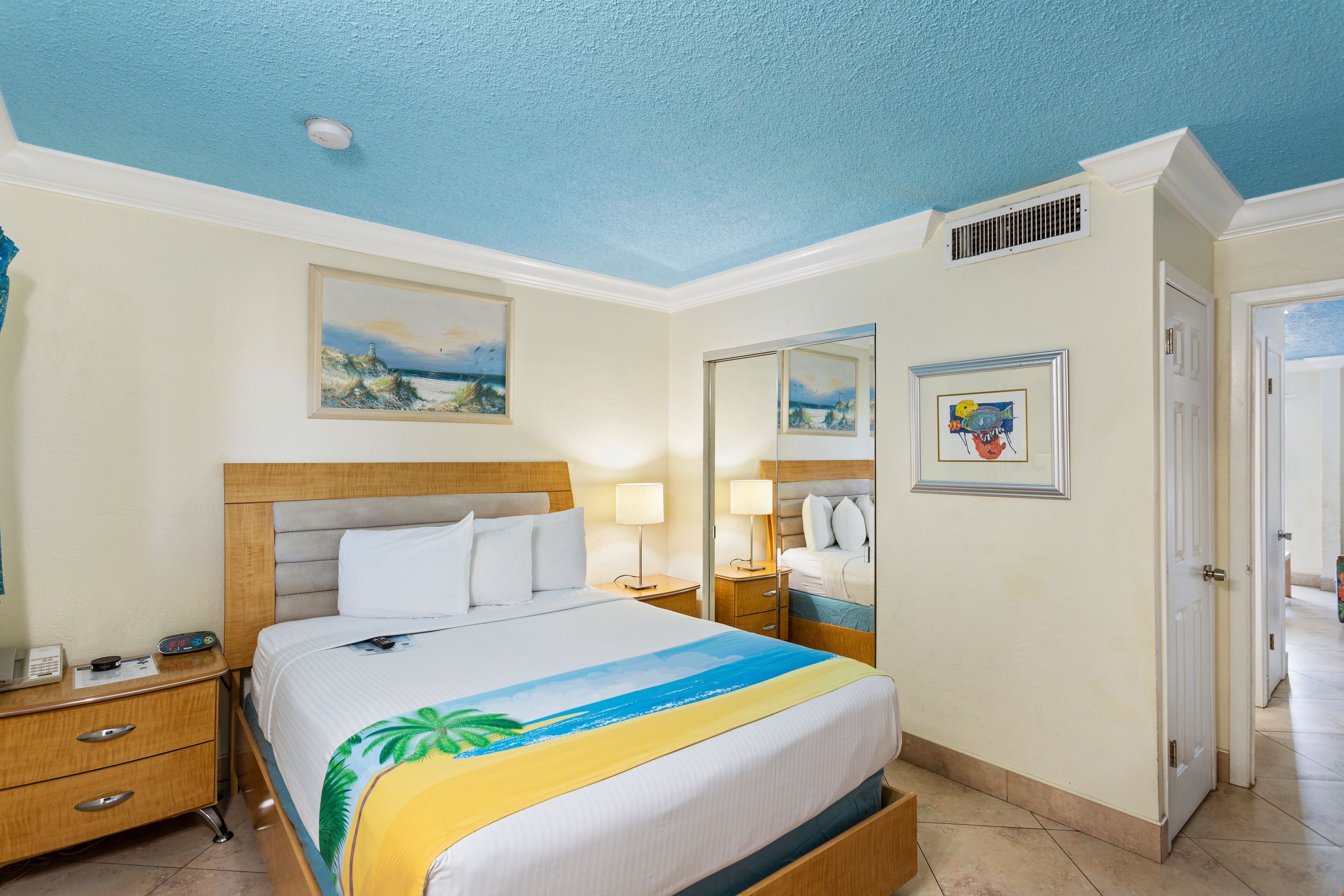 Een hotelkamer met een bed, nachtkastjes, een spiegel en een deur.