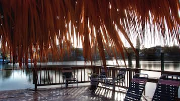 A covered outdoor seating area with chairs and a view of a calm body of water.