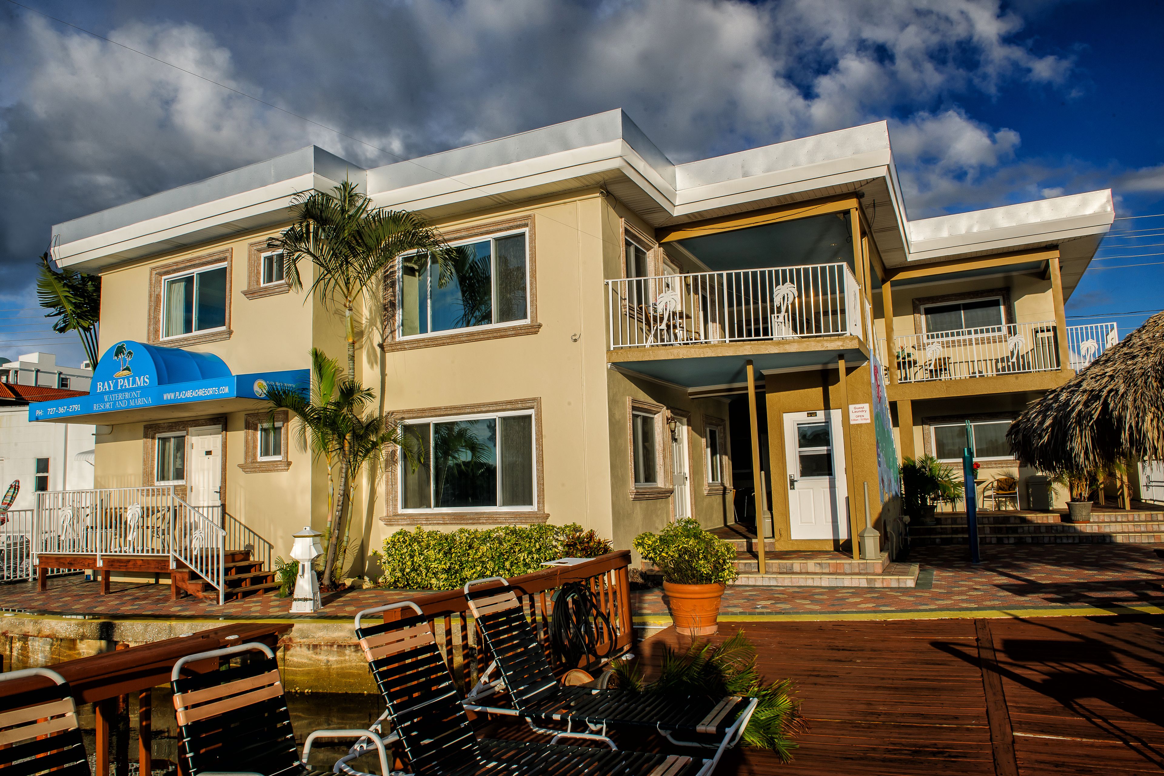 A hotel with a two-story structure, a balcony on the upper floor, and a patio area with wooden benches.