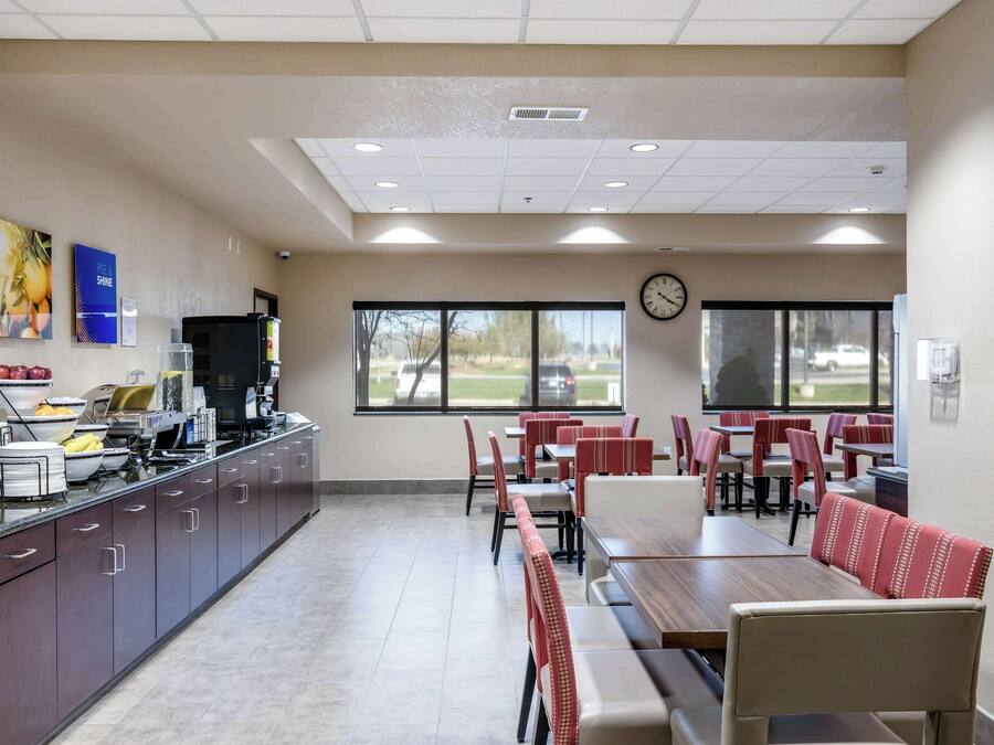 A restaurant with a long counter, multiple tables, and chairs.