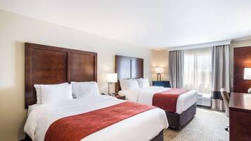 Habitación de hotel con dos camas, un escritorio y una silla.