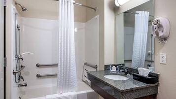 Ein modernes Badezimmer mit Badewanne, Dusche und Waschtisch mit Waschbecken und Spiegel.
