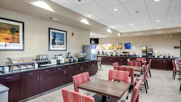 Een restaurantgedeelte in een hotel, met een buffet, zitplaatsen en kunst aan de muren.