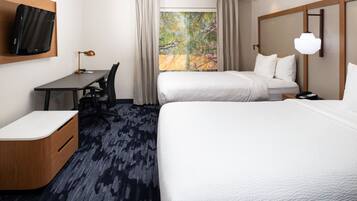 A hotel room with two beds, a desk, a chair, a TV, and a large window with curtains.