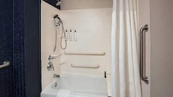 A bathroom with a bathtub, a shower, and handrails.