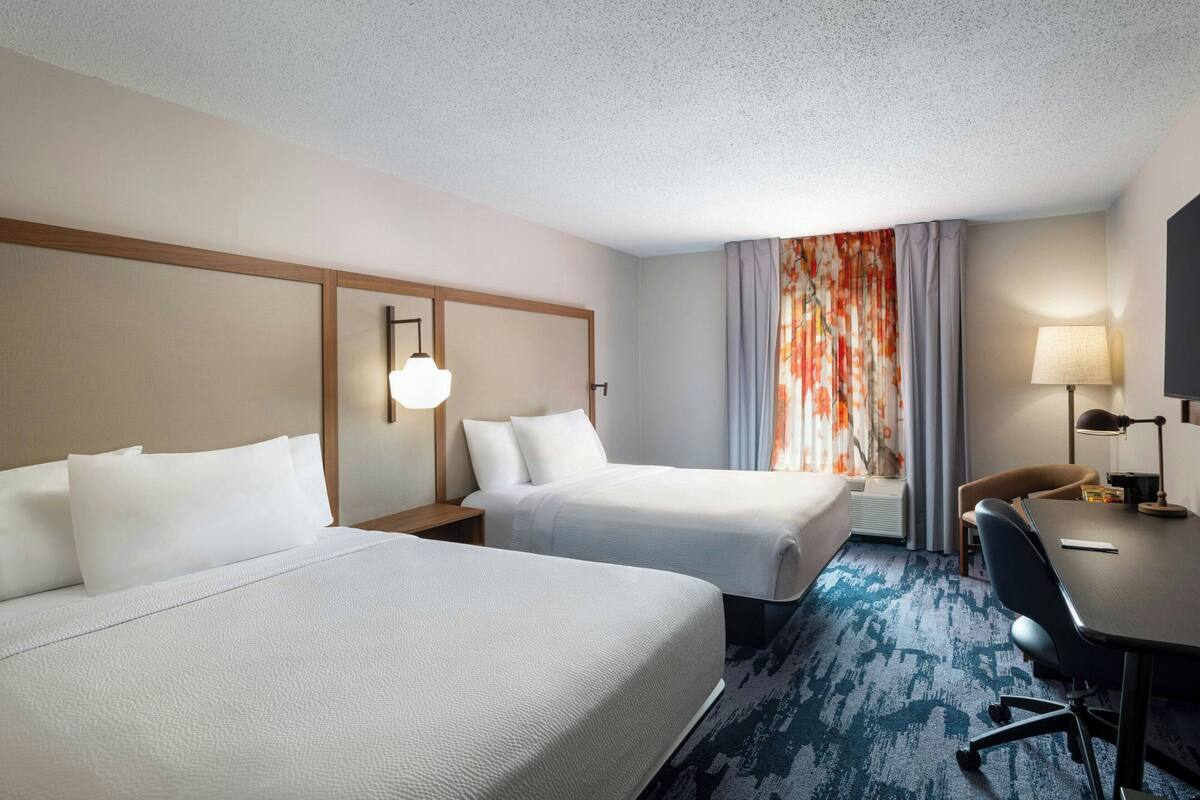 Een hotelkamer met twee bedden, een bureau en een stoel.