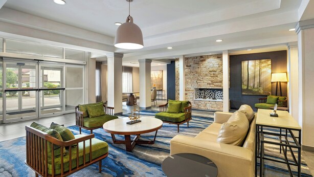 A spacious lobby with a large seating area, a fireplace, and a view through the glass doors.