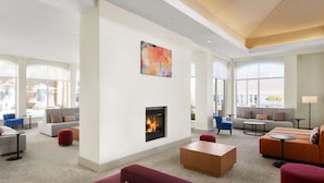 A spacious lobby with a fireplace, comfortable seating, and large windows. - Hilton Garden Inn Las Vegas/Henderson (Henderson)