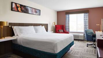 Habitación de hotel con una cama grande, un escritorio, una silla y una ventana con cortinas.
