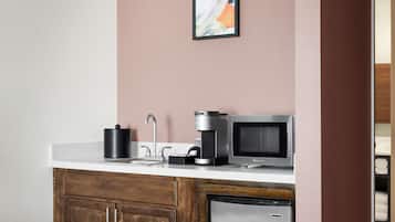 A kitchenette with a coffee maker, microwave, and refrigerator.