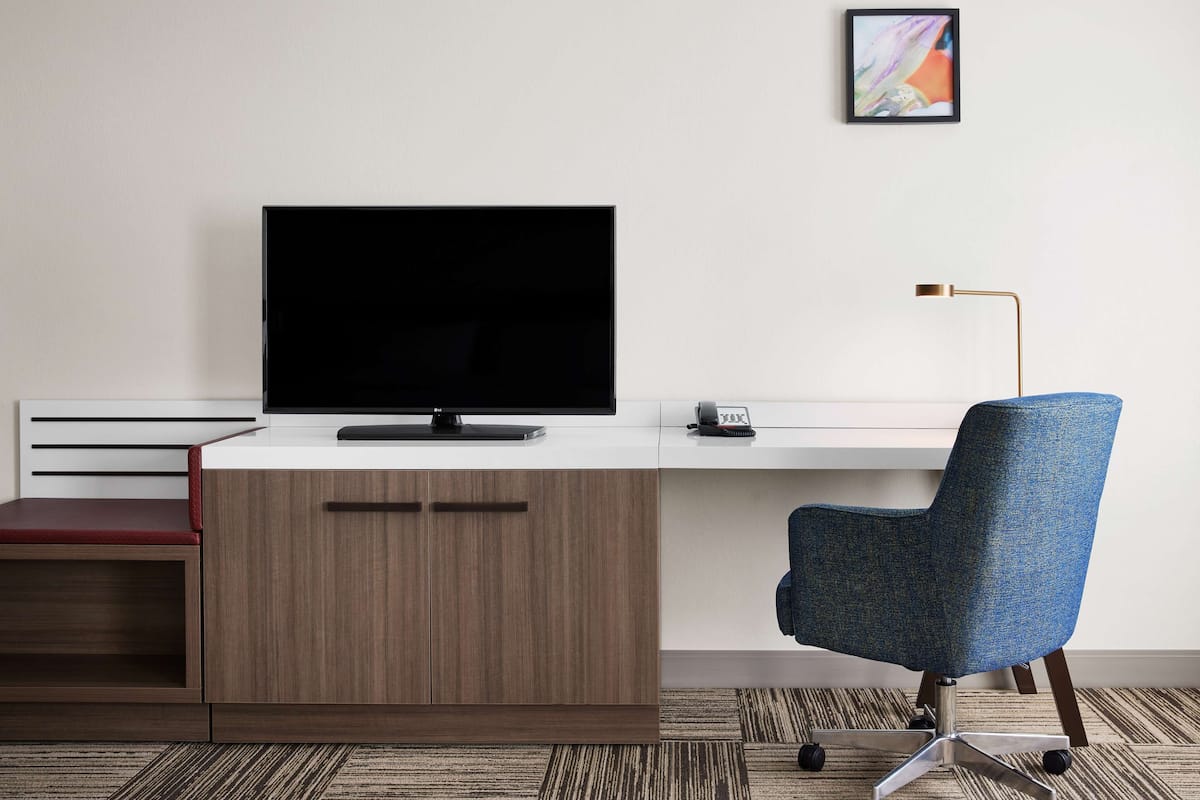 A modern office desk with a flat-screen monitor, a telephone, and a blue office chair.
