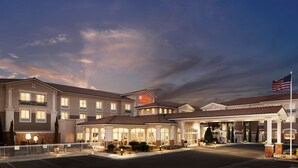 A hotel with a large entrance, a covered parking area, and an American flag. - Hilton Garden Inn Las Vegas/Henderson (Henderson)