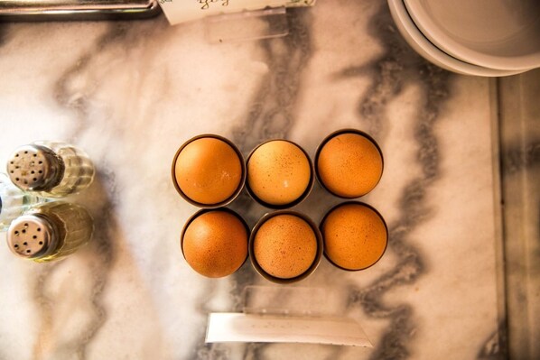 A top-down view of a kitchen counter with six eggs in a carton, salt and pepper shakers, and a white napkin.