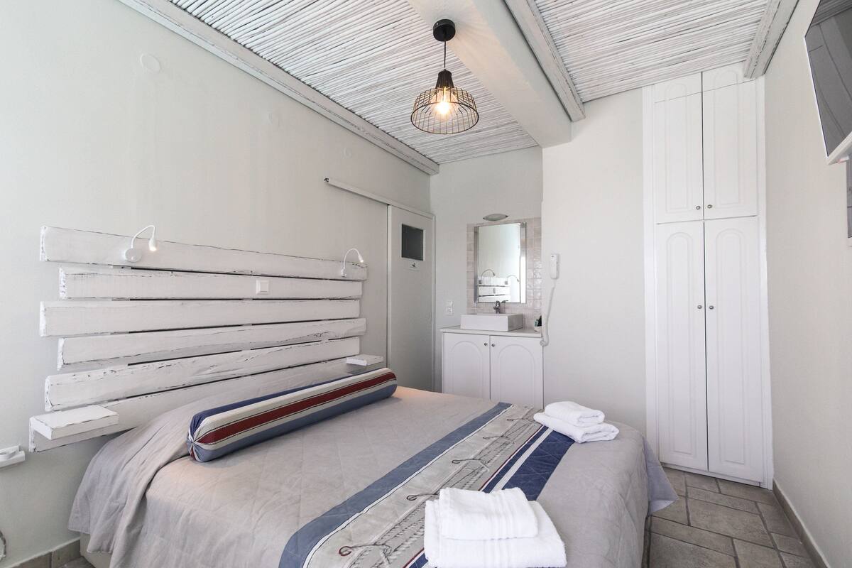 A bedroom with a bed, a bedside table, a wardrobe, and a hanging light fixture.